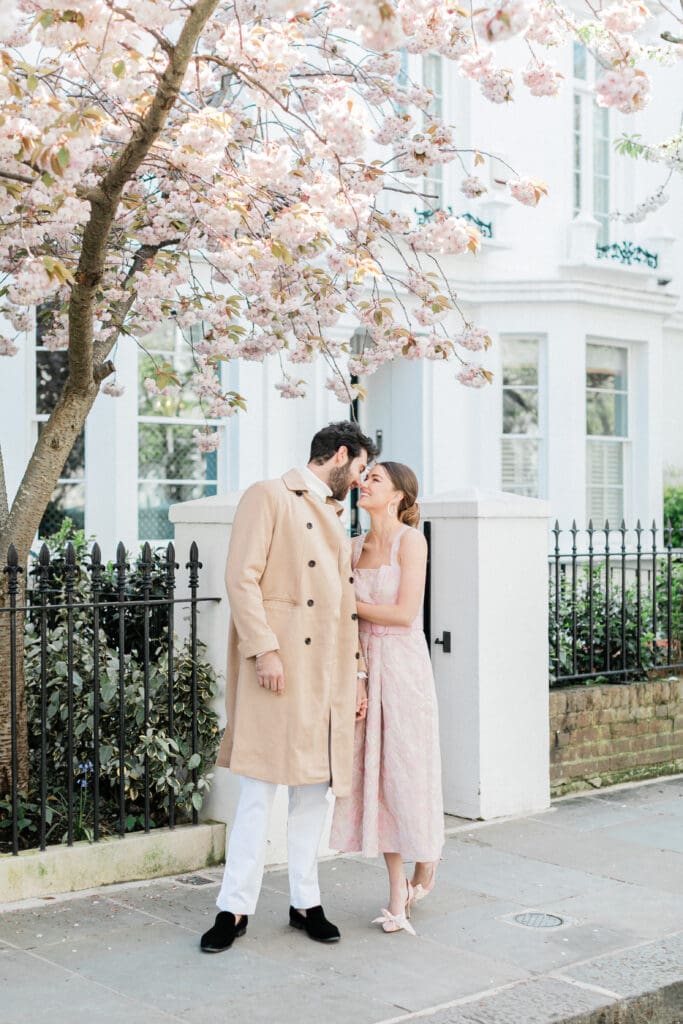 A couple posing outside a white townhouse for their engagement shoot in London's Notting Hill