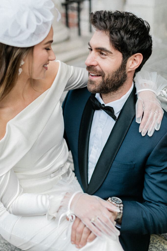 A close up of the bride and groom looking romantically at each other whilst sat on the steps of the entrance to The Goring.