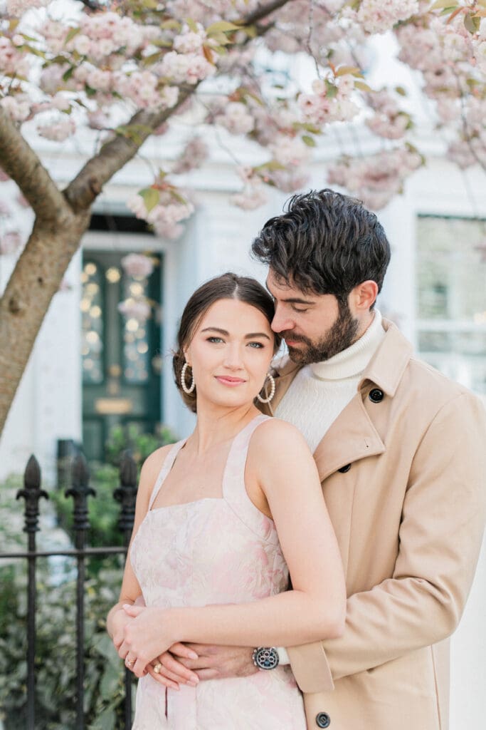 A couple posing outside a white townhouse for their engagement shoot in Notting Hill