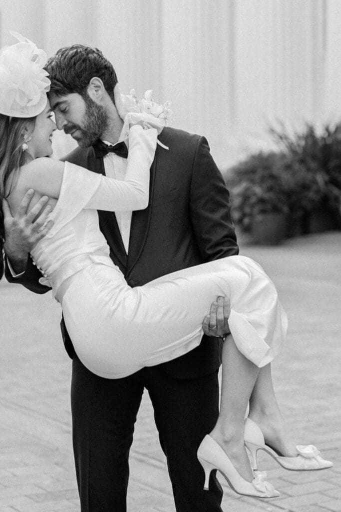 Groom romantically picking up his bride and holding her in a warm embrace.
