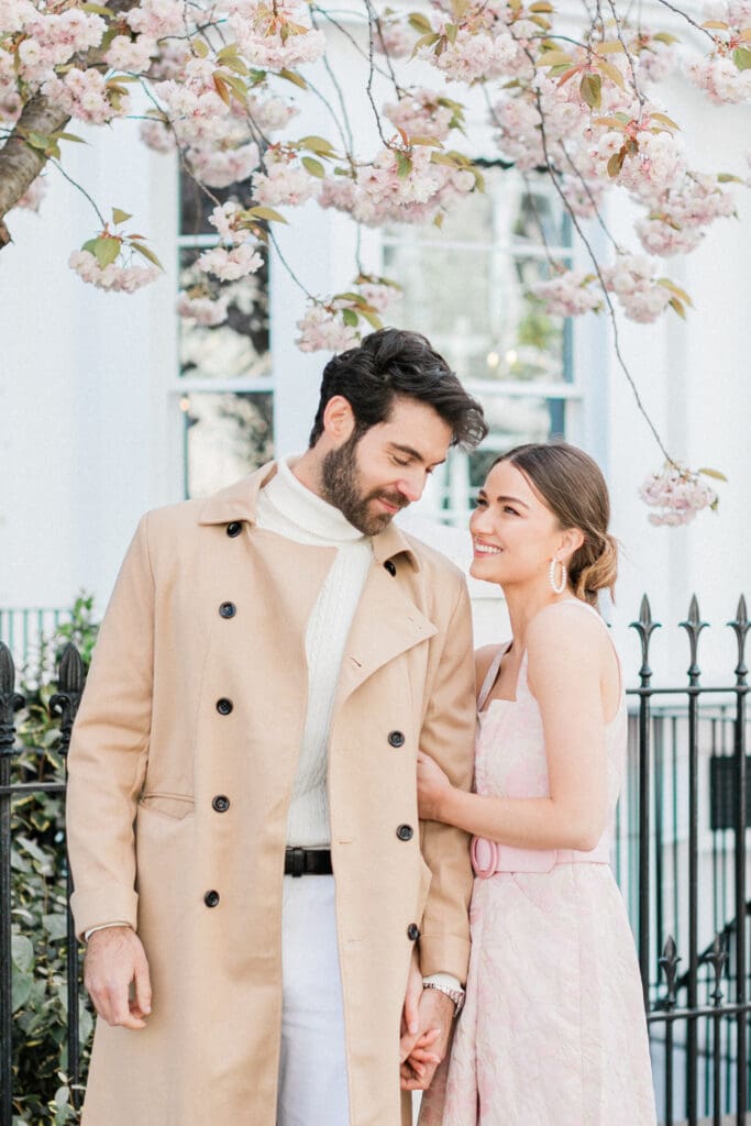 A couple posing romantically outside a white townhouse for their engagement shoot in Notting Hill