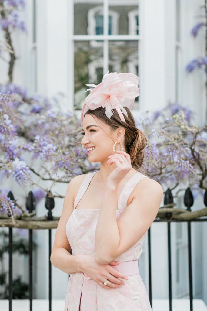 The bride posing for her engagement shoot with a backdrop of wisteria behind her for her engagement shoot in London.