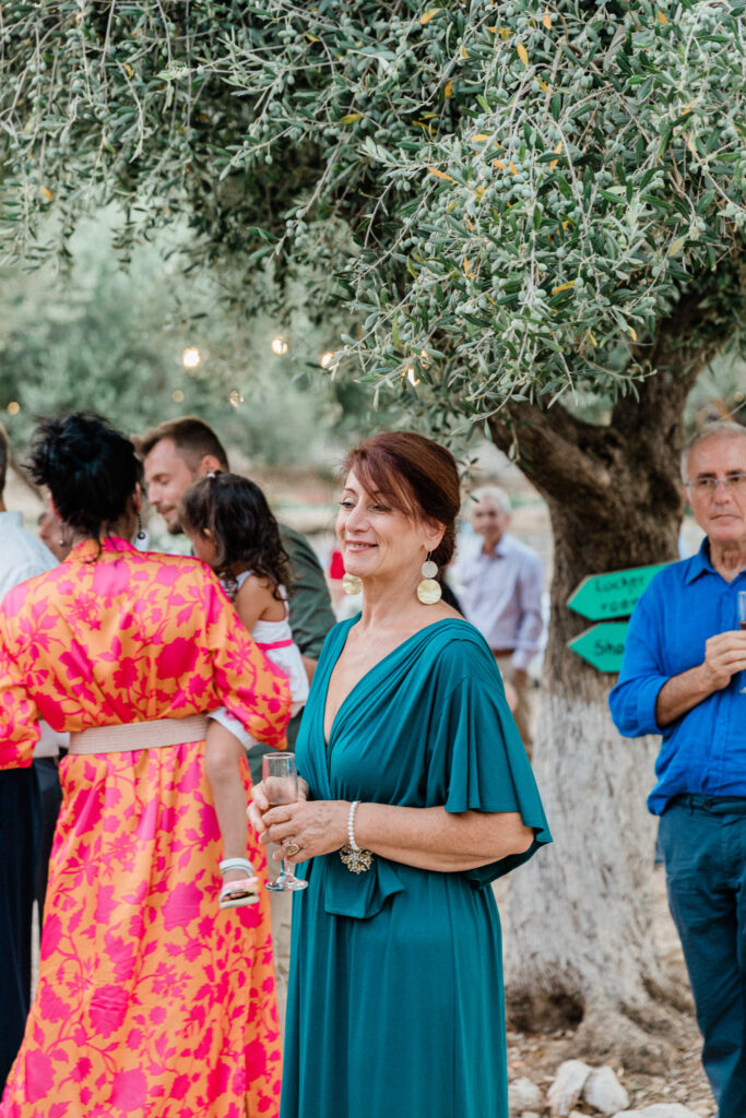 Wedding guest holding a glass of champagne at outdoor wedding reception in Ithaca, Greece.
