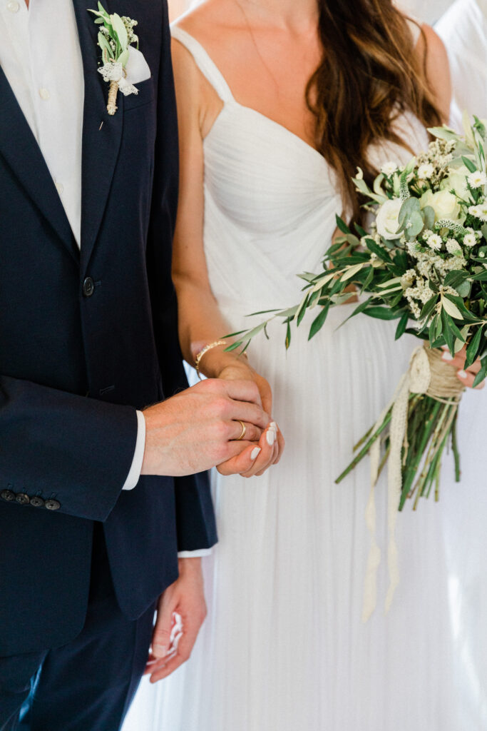 A close up of the bride and groom gently holding each others hands during their greek wedding ceremony.