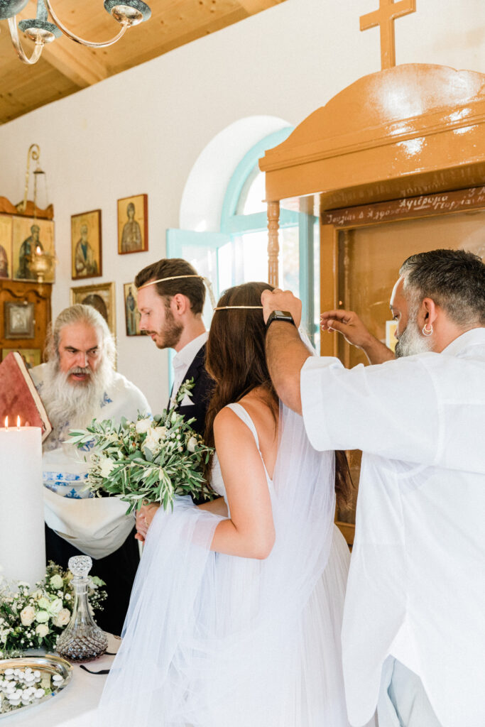 The bride and groom performing traditional Greek practices during their wedding ceremony.