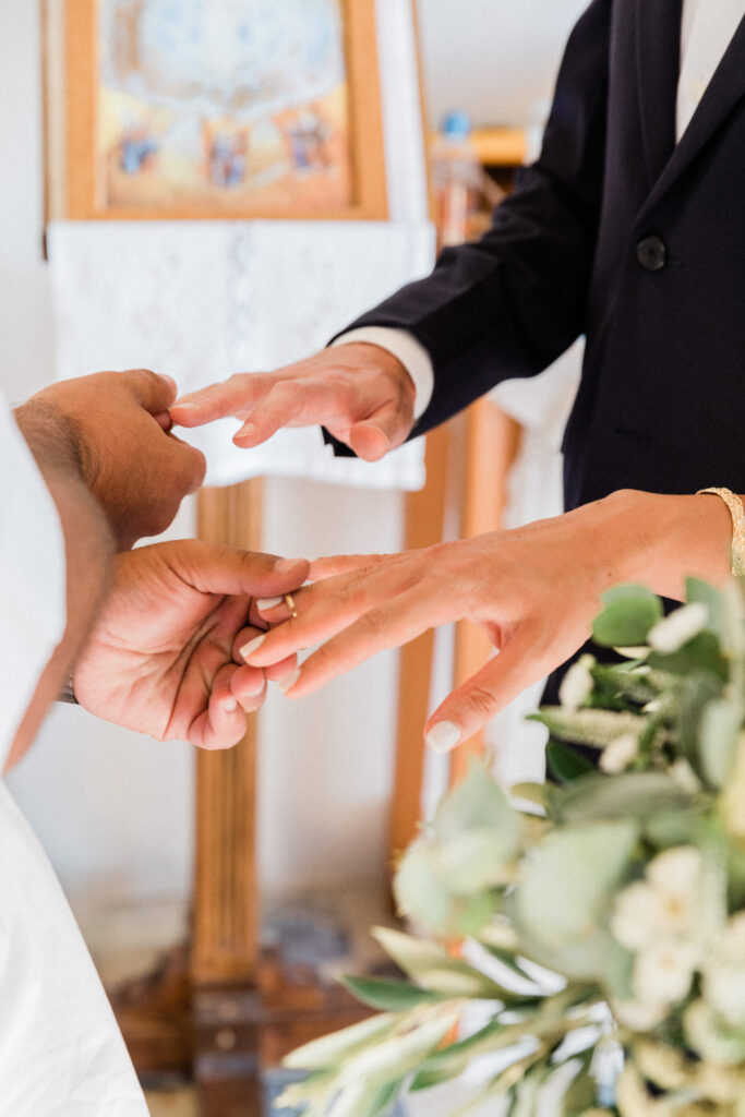 A close up of the bride and grooms hands exchanging wedding rings.