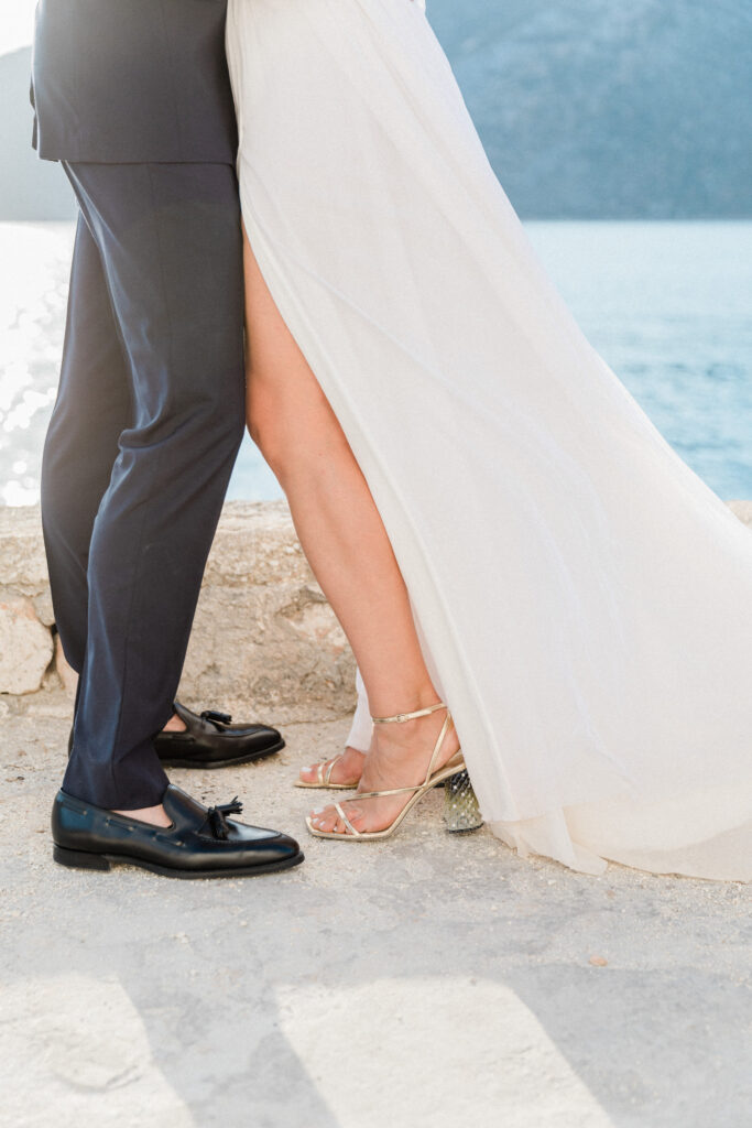 A close up of the bride and groom's legs standing in their wedding shoes.